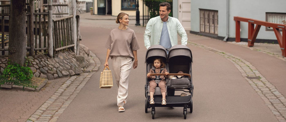 parents push children in double stroller