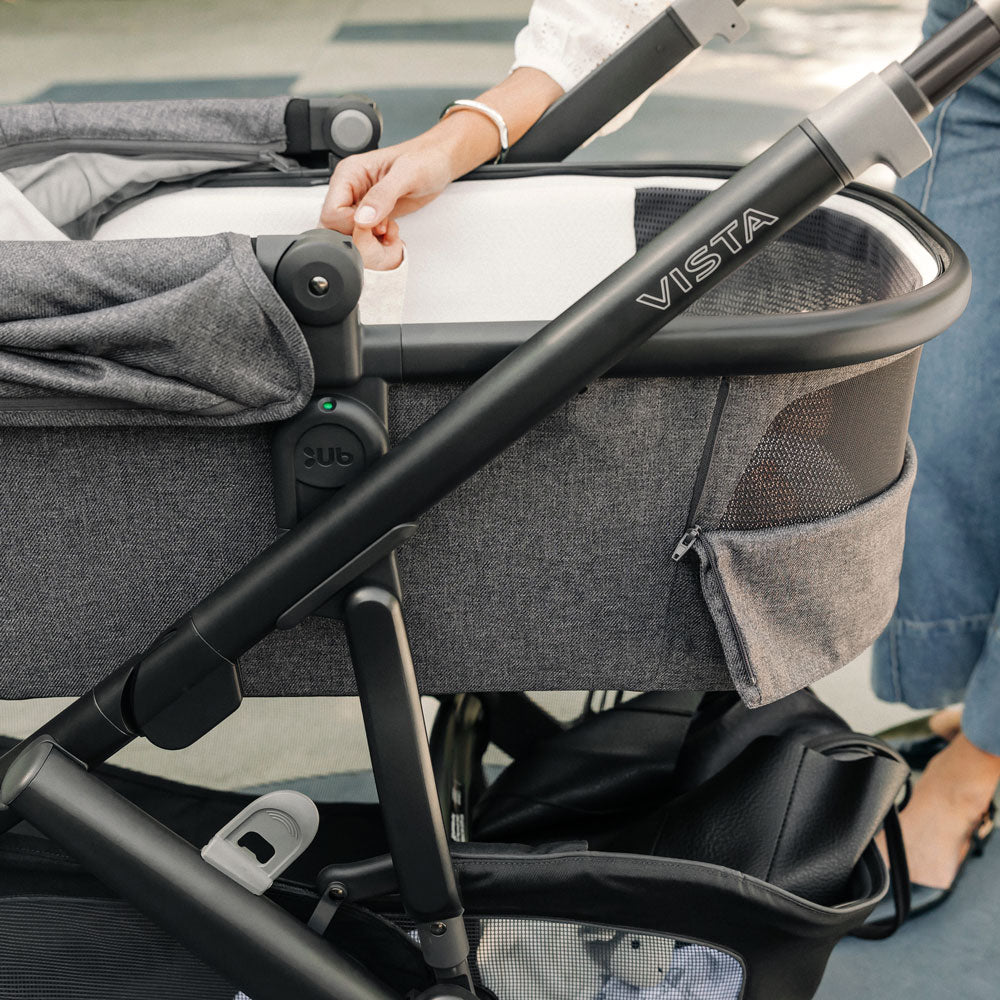 Baby in UPPAbaby Bassinet V3 - GREYSON (Charcoal Melange) holds moms hand