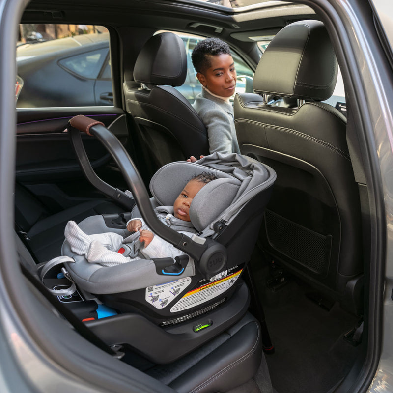 Mom looks back to check on infant in UPPAbaby ARIA Infant Car Seat - ANTHONY (Light Grey)