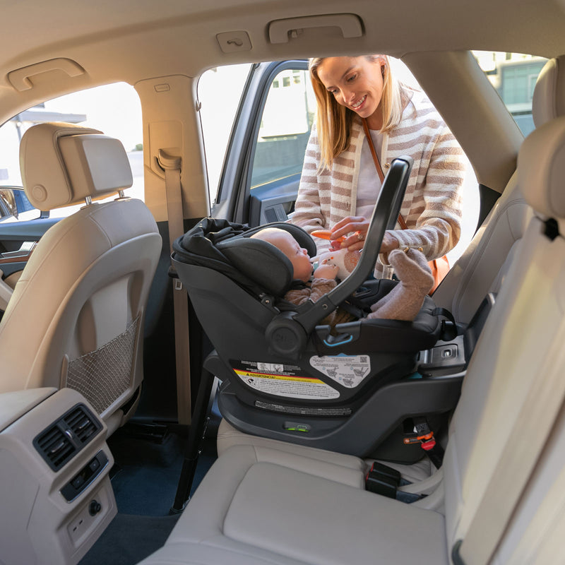 Mom putting UPPAbaby ARIA Infant Car Seat - JAKE (Charcoal) in her vehicle