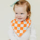 Little girl smiles while wearing Copper Pearl Single Holiday Bandana Bib - Mickey Mouse's Boo Bash - Check