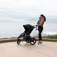 Mom holds toddler while holding handlebar of Bumbleride 2024 Speed Jogging Stroller - Black