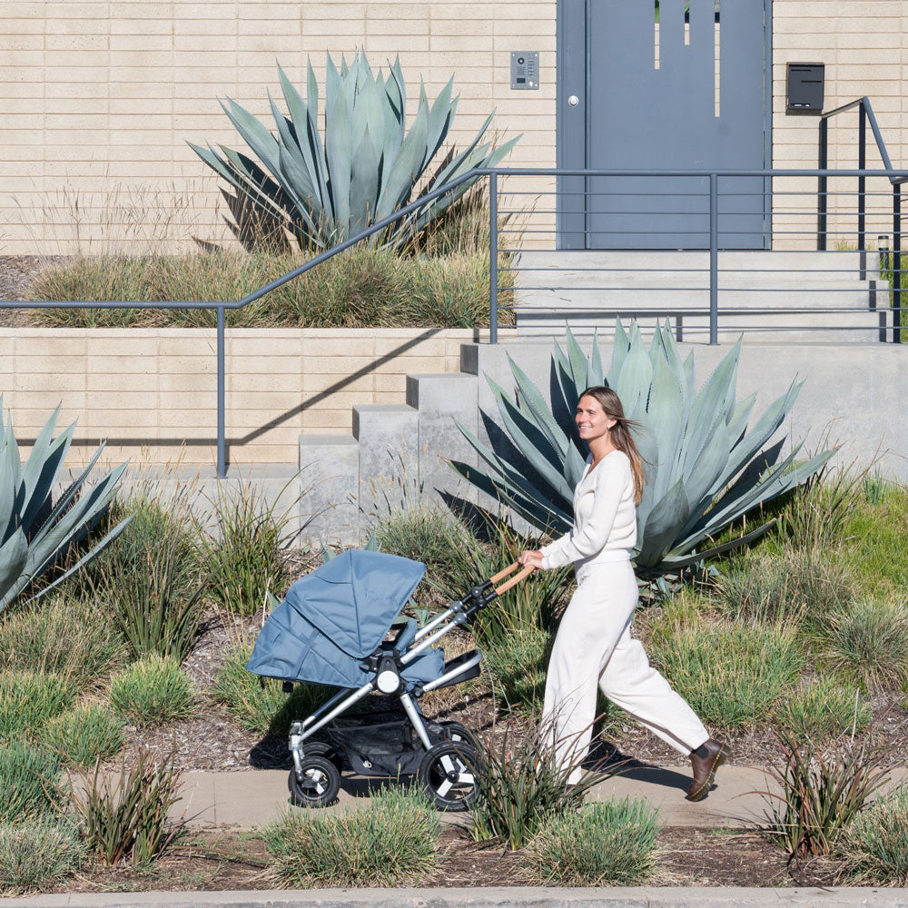 Mom smiles while pushing newborn baby in Bumbleride 2024 Era Reversible Stroller - Ocean