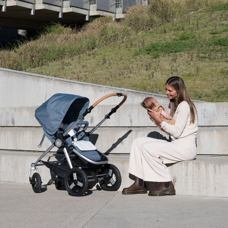 Mom holds baby while sitting next to Bumbleride 2024 Era Reversible Stroller - Ocean