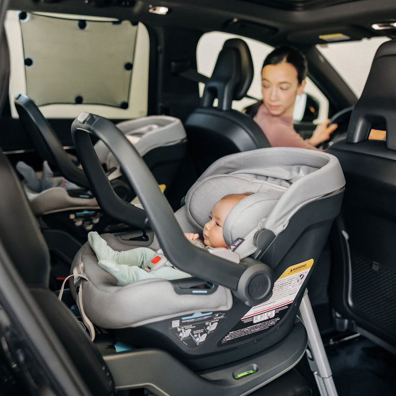 Mom looks back at babies in infant car seats with UPPAbaby Easy-Fit Sunshade attached to the window