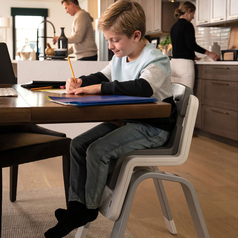 Boy does his homework while sitting in Nuna ZAAZ High Chair with MagneTech Secure Snap - Carbon