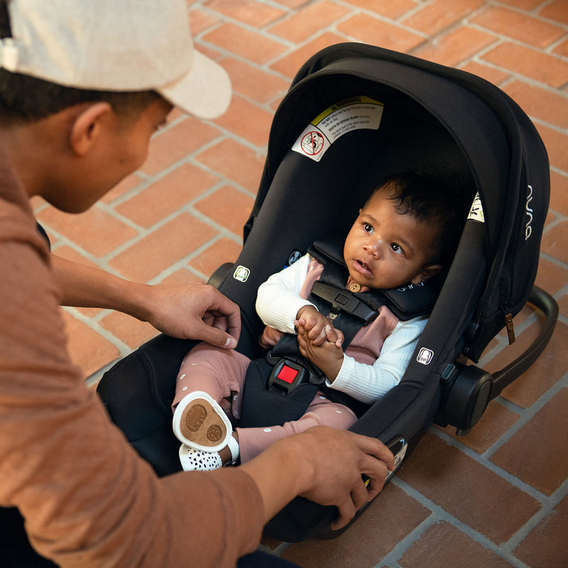 Baby sitting in Nuna PIPA Aire Infant Car Seat with Base - Caviar