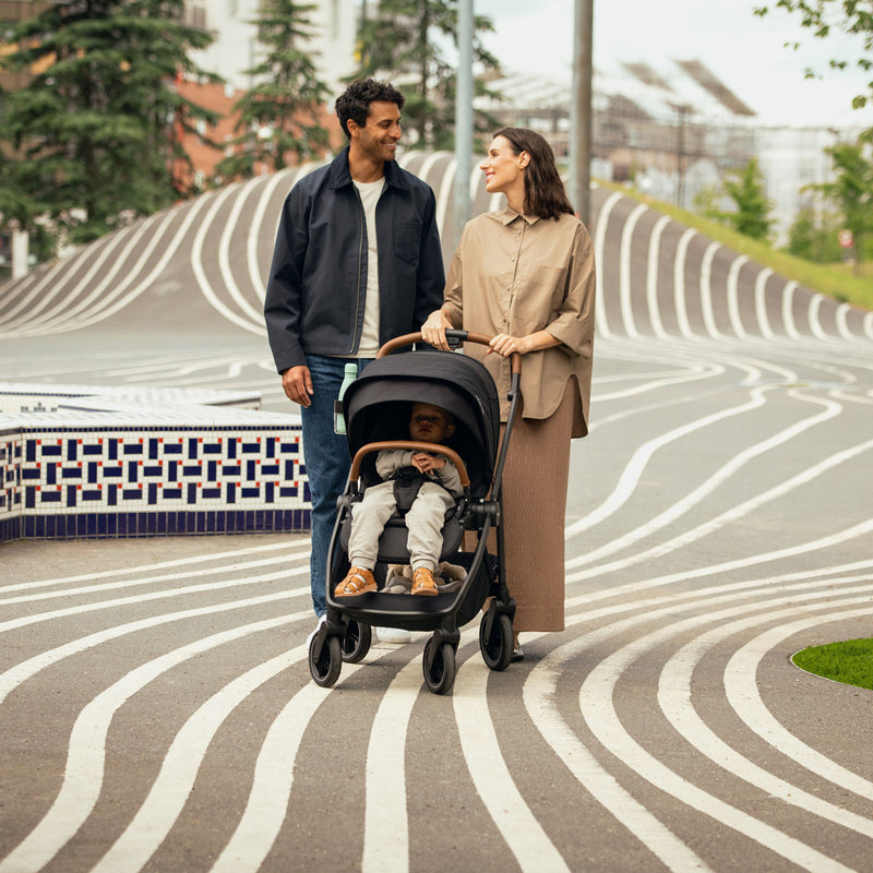 Woman smiles at man while pushing Nuna SWIV Stroller - Caviar