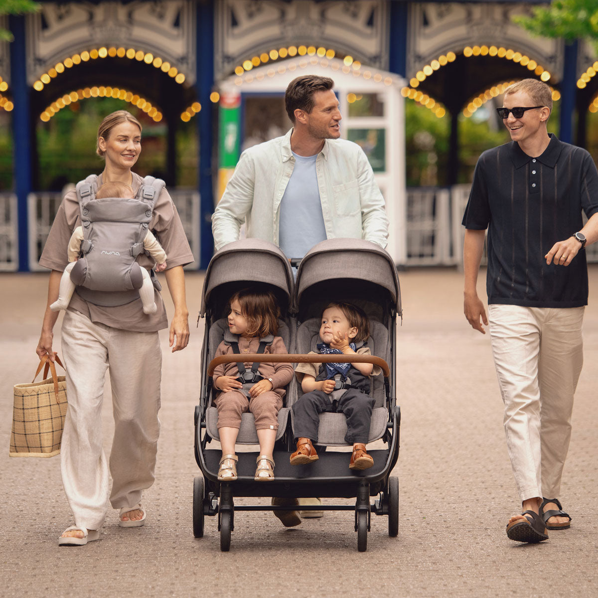 Dad pushes toddlers in Nuna TRVL Dubl Stroller - Granite at amusement park