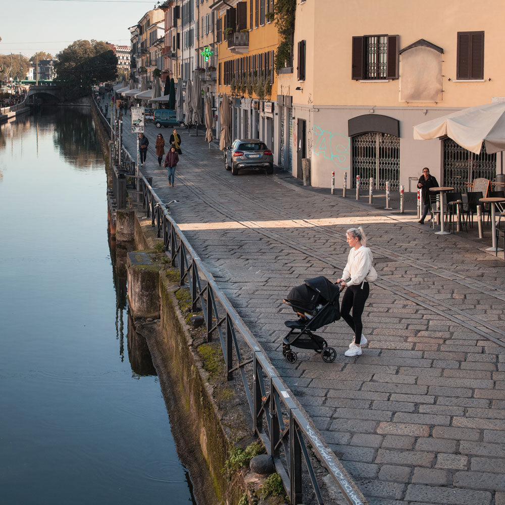 Mom exploring Europe while baby rides in Nuna TRVL LX Stoller and PIPA Urbn Car Seat Travel System - Caviar