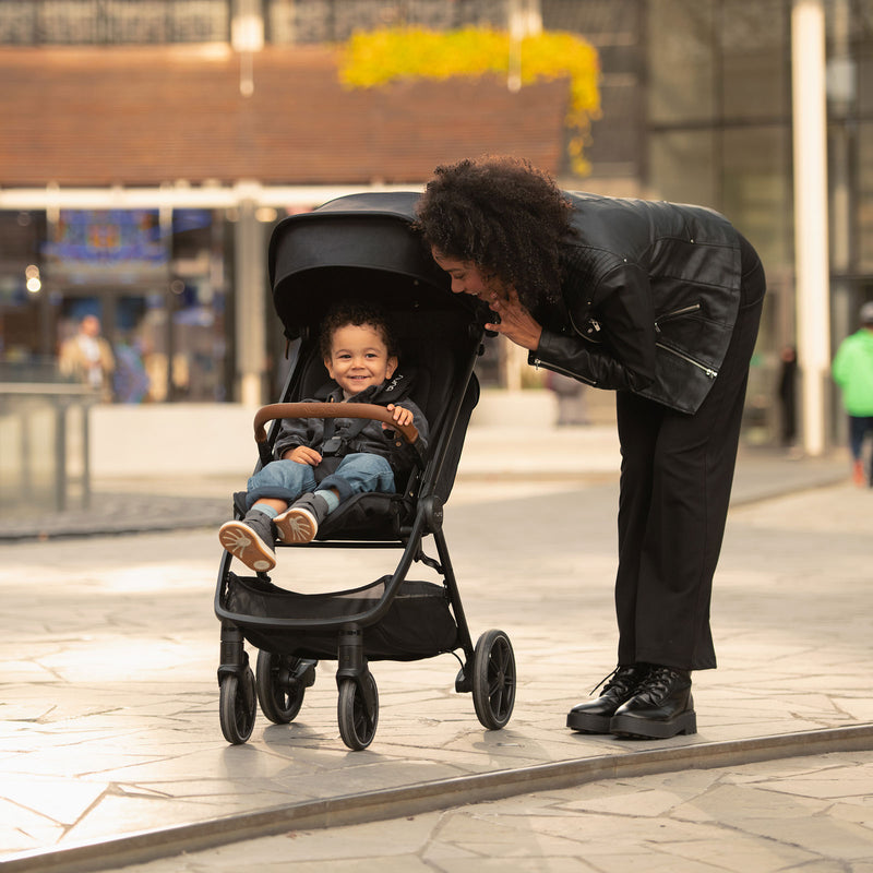 Mom talking to child sitting in Nuna TRVL LX Stroller - Caviar