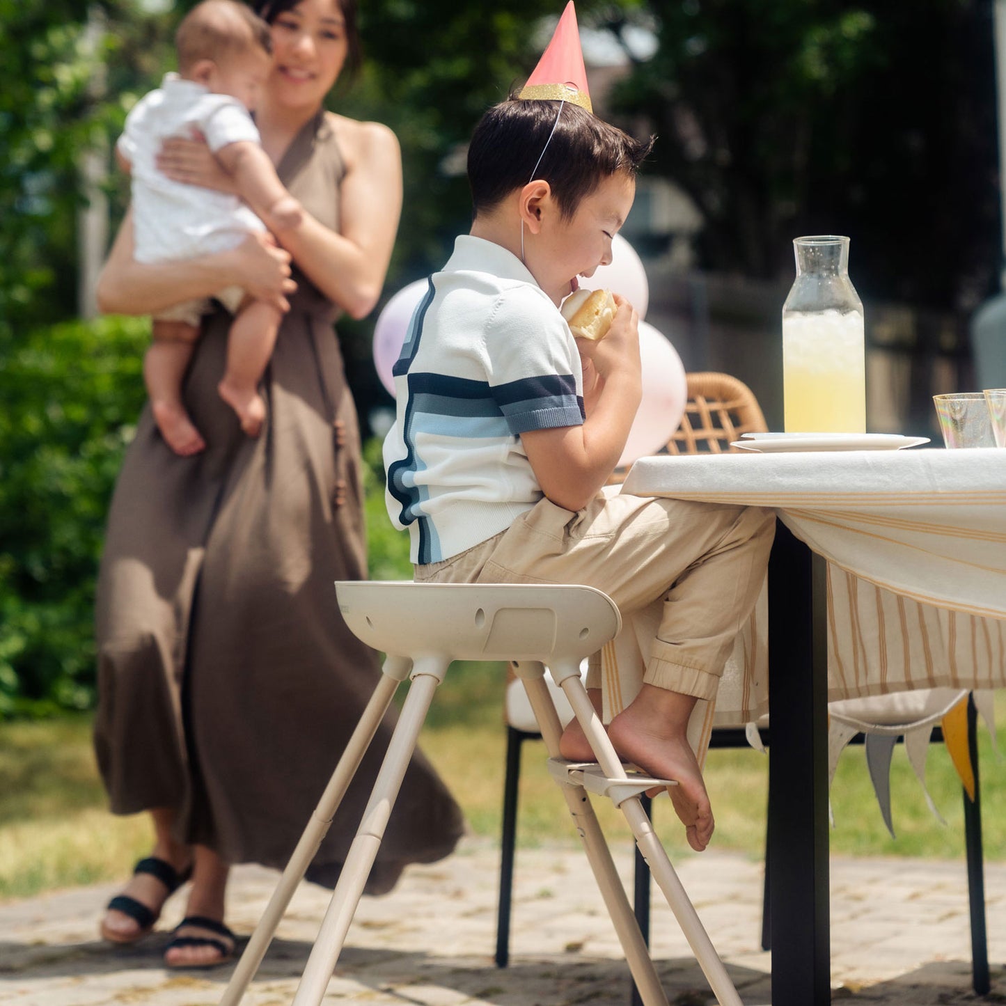 Little boy eats a snack while sitting in Maxi-Cosi Moa 8-in-1 High Chair - Classic Oat