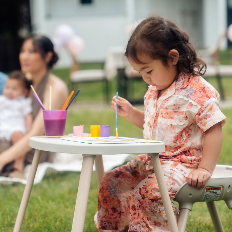 Little girl paints a picture on Maxi-Cosi Moa 8-in-1 High Chair - Classic Oat