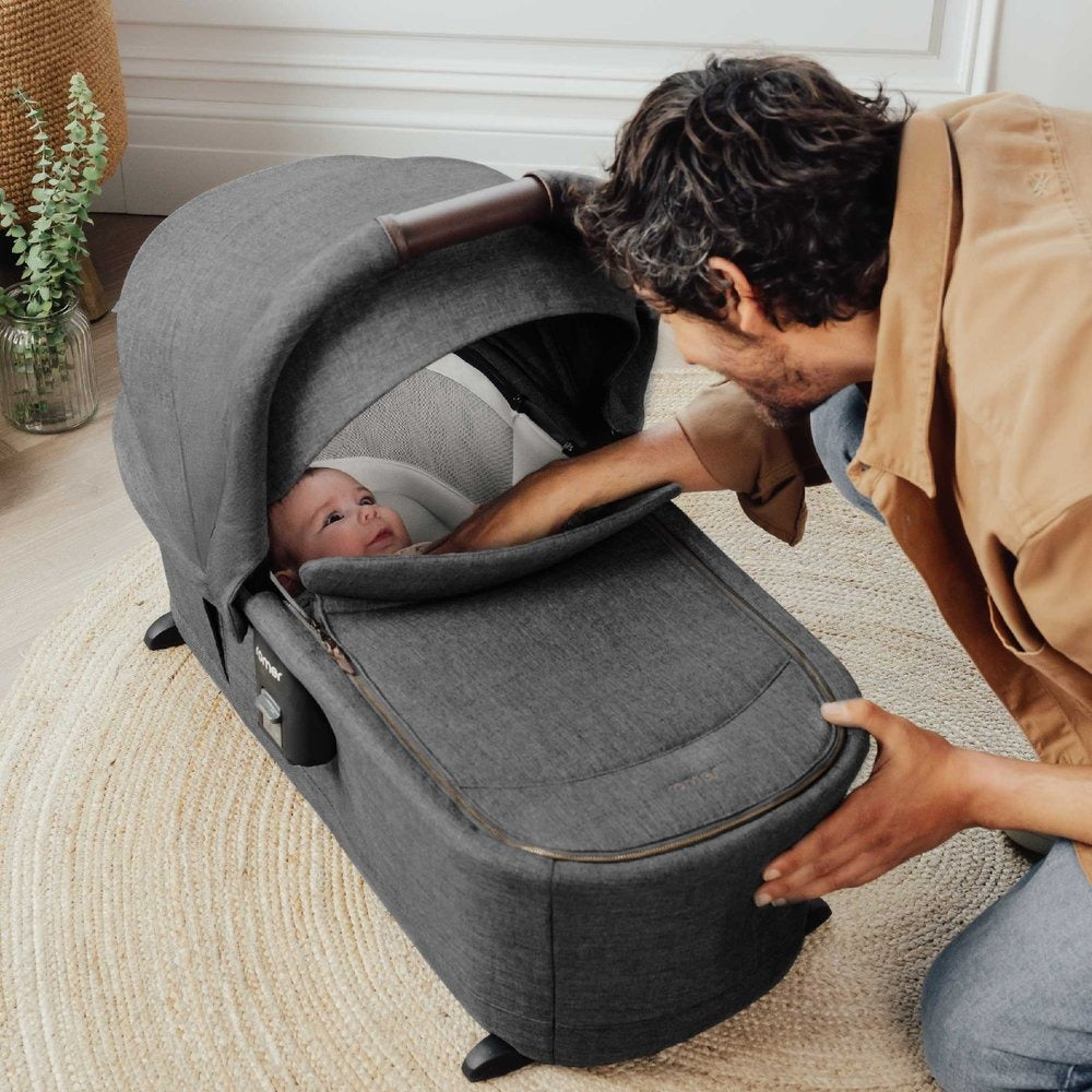 Dad looks at baby lying in Romer Sera Bassinet - Peppercorn