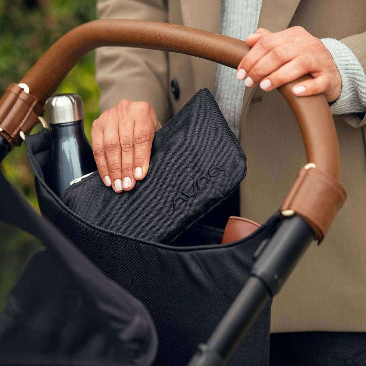 Woman places bag into Nuna Stroller Organizer - Caviar