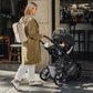 Woman pushes baby in Romer Juni Infant Car Seat - Peppercorn attached to Romer Tura stroller