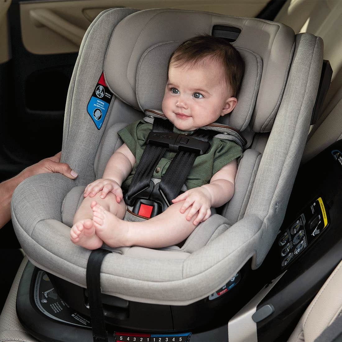 Baby sits in Nuna REVV Rotating Convertible Car Seat - Hazelwood