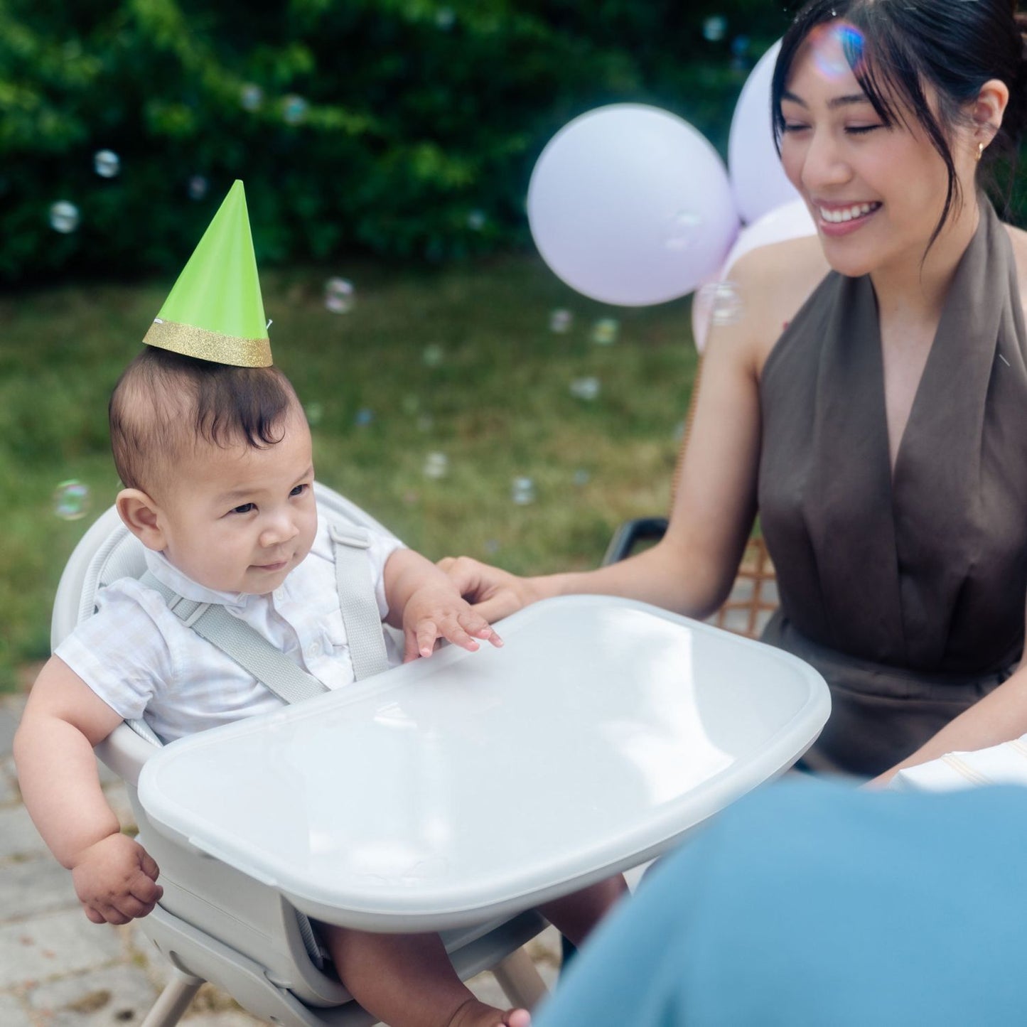 Mom smiles at baby sitting in Maxi-Cosi Moa 8-in-1 High Chair - Classic Oat