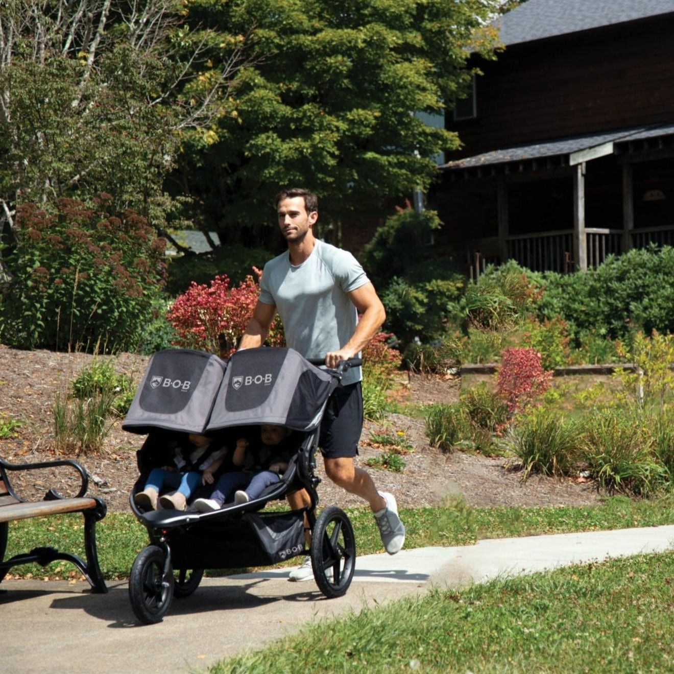 Man jogs with BOB Revolution Flex Duallie 3.0 Double Jogging Stroller with kids inside - Graphite Black