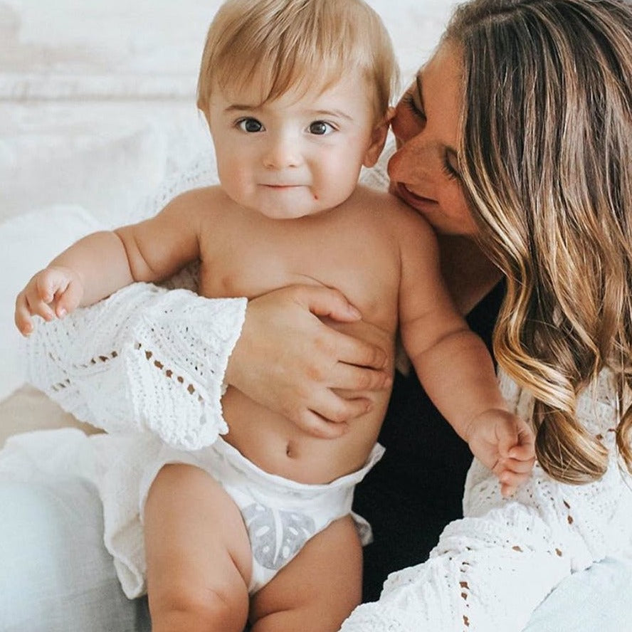 Mom holding baby wearing Parasol Co Clear and Dry Diapers