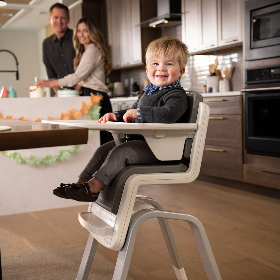 Toddler sitting in Nuna ZAAZ High Chair with MagneTech Secure Snap - Carbon