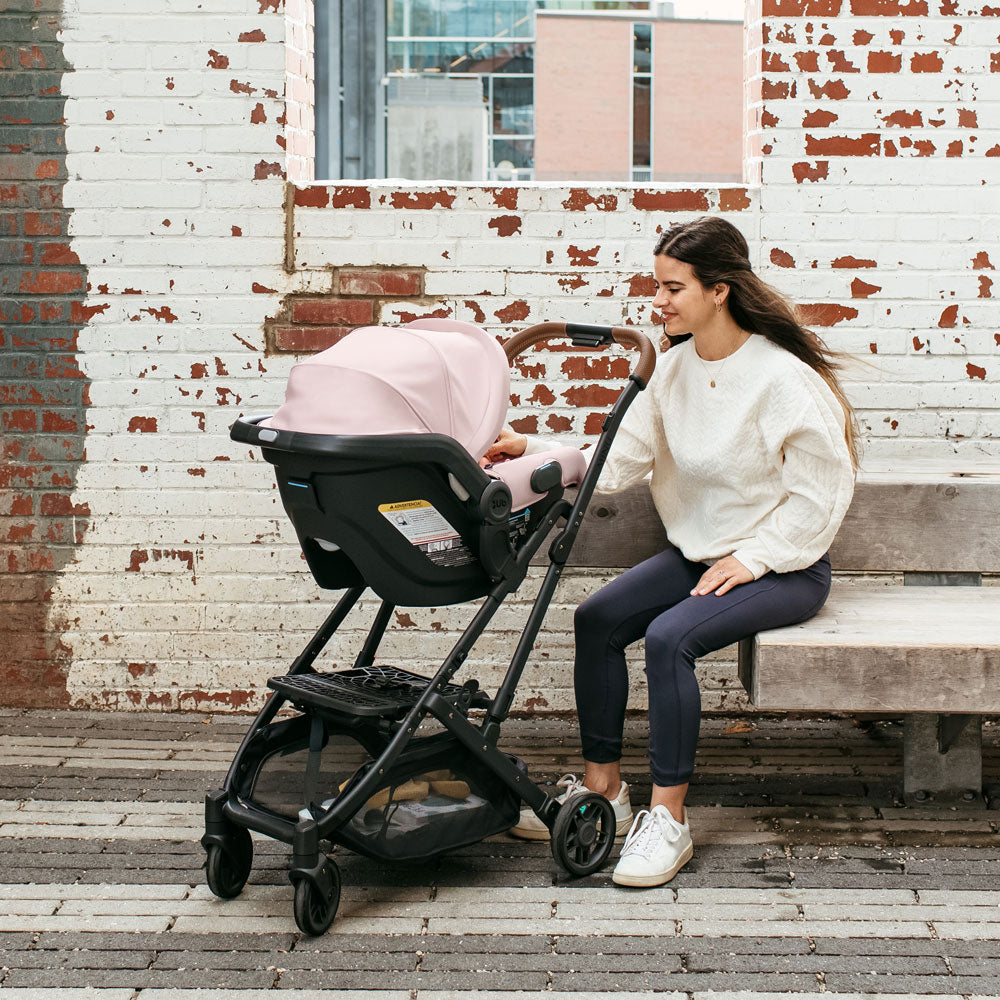 Mom looking at baby in the UPPAbaby MESA V2 Infant Car Seat - ALICE (Dusty Pink)